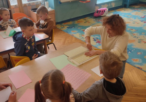 Mama Tymka prezentuje dzieciom jak trzeba przecinać kartkę papieru