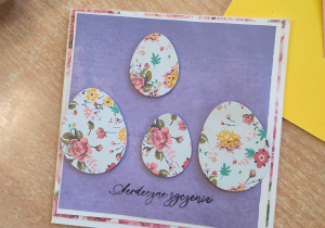 Kartka wielkanocna na fioletowym tle z czterema jajkami w kwiatki
