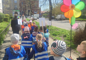 Dzieci idą chodnikiem jeden za drugim z plakietkami o środowisku