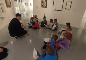 Dzieci siedzą wokół obrazów i instalacji w Muzeum