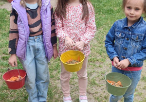 Dziewczynki trzymają w wiaderkach jedzenie dla alpak