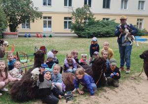 Zdjecie grupowe z alpakami i panem prowadzącym