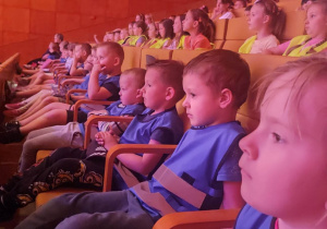 Dzieci siedzą w sali koncertowej na swoich miejscach i oglądają spektakl