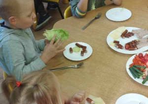Dzieci jedzą pyszne kanapki przy stole.