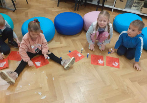 Dzieci przyklejają piórka na kartke