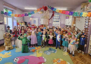 Zdjęcie grupowe wszystkich przebranych dzieci na balu na tle serpentyny oraz kolorowe girlandy.