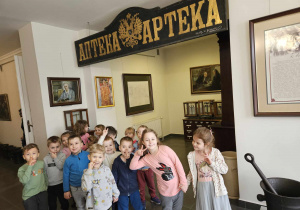 Zdjęcie grupowe przy starym napisie APTEKA